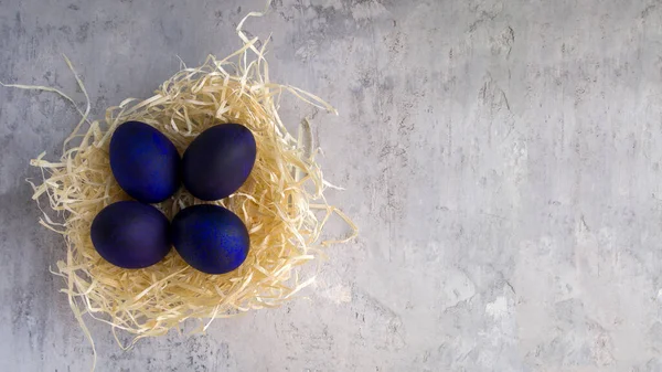 Tarafsız gri arka planda saman yuvasında olağandışı mor Paskalya yumurtaları. Metin (kopyalama alanı) için çok yer var. Paskalya için güzel yumurta tasarımı.