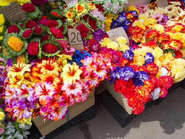 Selling colorful plastic flowers on the street market. Eastern European tradition to decorate the grave in the cemetery with artificial flowers. Bright sleaze - a disaster for ecology and environment.