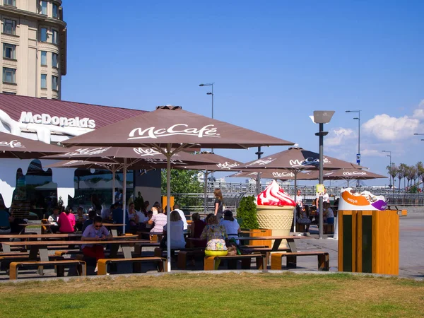 Caddedeki masalar ve banklar markalı şemsiyelerin altında McCafe. Poshtova Meydanı 'ndaki (Podil Bölgesi) Mcdonalds. Kyiv, Ukrayna - Eylül 2019