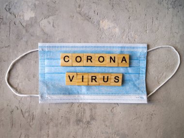 CORONAVIRUS kelimesi mavi cerrahi maskelerin arka planında ahşap harflerle kaplıydı..