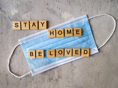 Sözcükler, mavi cerrahi maskenin arka planında ahşap harflerle kaplanmış bir şekilde sevilir. Coronavirüs salgını sırasında Sevgililer Günü.