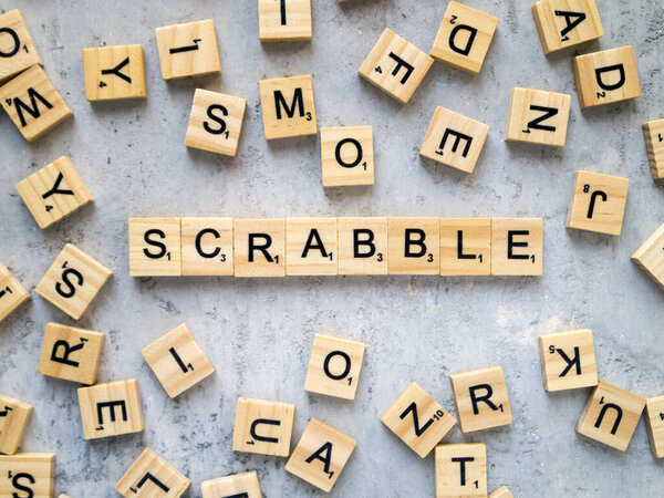 Игра в скраббл. Верхний вид деревянных букв на сером фоне. Январь 2021 - Киев, Украина