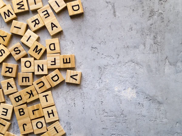 Latin alfabesinin gri arka plandaki harflerinin üst görüntüsü. Yüzeyin bir kısmı boş. Boşluğu kopyala.