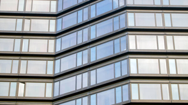 Part of a modern gray building with large windows. One window is open.