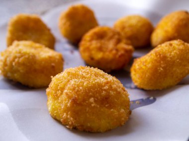 Beyaz kağıtta peynirli kroketlerin yan görünüşü. Lezzetli aperatif.