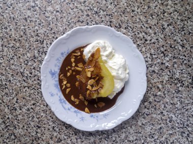 Krem şanti, çikolata sosu ve badem gevreğiyle kaynatılmış karamelli armut. Fransız poire belle Helene.