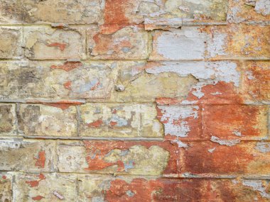 Renkli bir tuğla duvarın yan görüntüsü. Yüzey boya lekeleriyle kaplı..