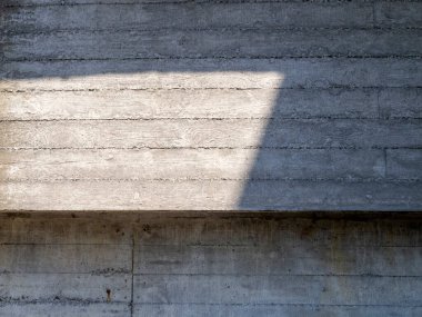 Üzerine bir gölge düşen ahşap paneller desenli beton bir duvar parçası..