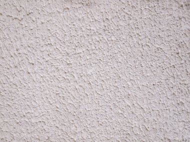 Kirli, beyaz, pürüzlü yüzey. Granüler alçı. Duvarda düzensiz bir şekil var..