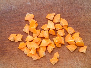 Tahta bir tahtanın üzerinde doğranmış havuç yakın çekim. Paysanne kesimi.