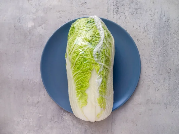 Mavi bir tabakta selofana sarılı taze Çin lahanası..