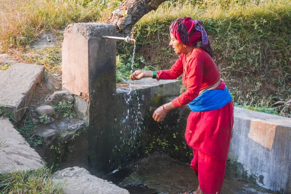 Nepalli köylü kadın, Nepal 'in kırsal kesimindeki musluk suyuyla yüzünü yıkıyor. Nepalli kırsal köy kadını