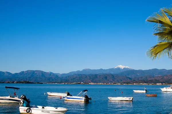 Mavi gökyüzü, mavi deniz ve kıyıda küçük balıkçı tekneleri.