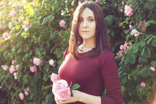 Portrait d'une fille en robe de couleur marsala. Elle tient des roses . — Photo