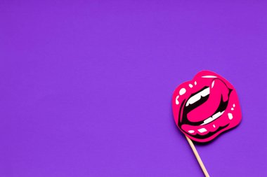 Pembe, dişi, seksi dudaklar, beyaz dişler ve çıkıntılı bir dil. Sağ alt köşede şablon. Güzel, yumuşak, mor bir arka plan.