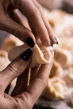 Siyah manikürlü kadın elleri mutfakta köfte heykeli yapıyor.