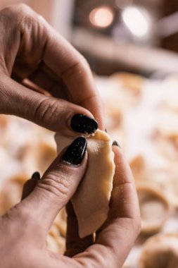 Siyah manikürlü kadın elleri mutfakta köfte heykeli yapıyor.