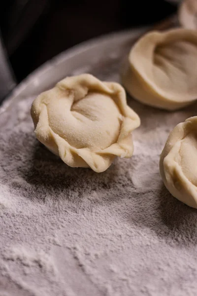 Tahta bir tahtanın üzerine un serpiştirilmiş el yapımı etli börekler.