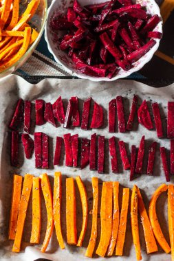 Düzgün beslenme ile sağlıklı bir atıştırmalık. Taze havuç ve pancar, baharat ve şifalı otlar halinde dilimlenmiş, parşömen üzerine parşömen üzerine serilmiş, masada kurusıkı tabaklar ile birlikte.