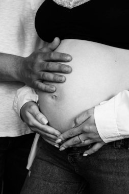 Ebeveynlerin elleri hamile kadınların karnında yatar. Genç ebeveynler bebek bekliyor.