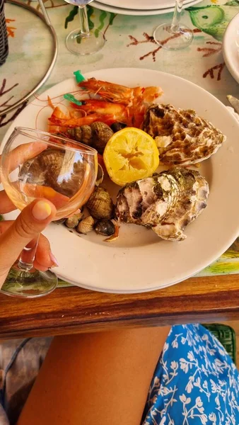 Plate of seafood on the table in front of a girl on vacation — Stock Photo, Image