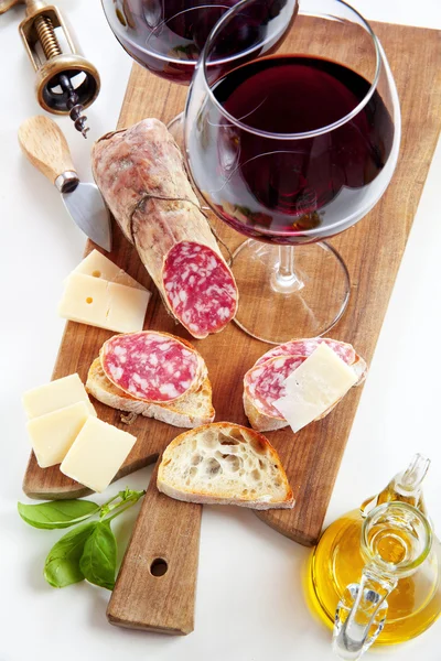 Two wineglass with red wine and assortment of cheese and salami. — Stock Photo, Image