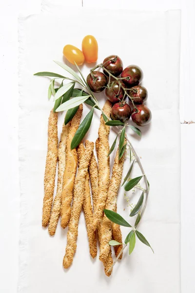 Цветные помидоры, хлебные палочки с кунжутом, оливковое масло и — стоковое фото