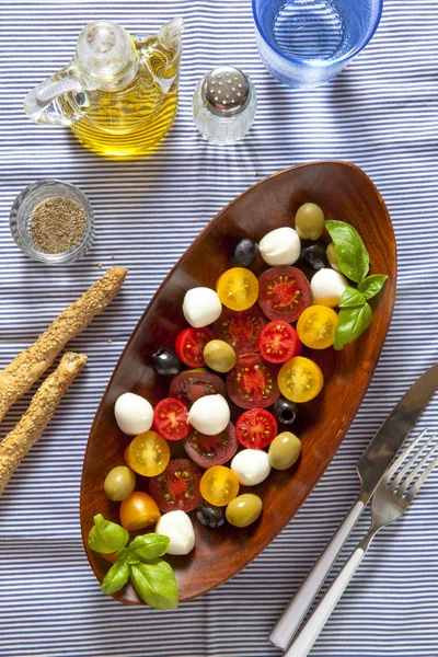 Ensalada con tomates de colores, mozzarella pequeña, aceitunas verdes y b —  Fotos de Stock