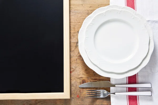 Leeg bord met bestek op een houten achtergrond en een zwarte chal — Stockfoto