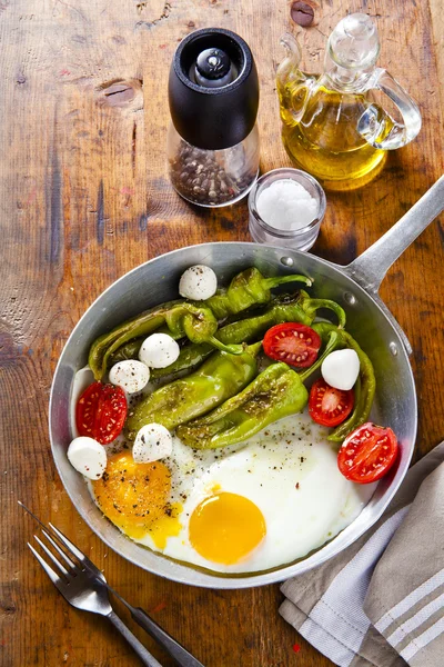 Breakfast in a frying pan. fried eggs with salad. fried green pe — Stock Photo, Image
