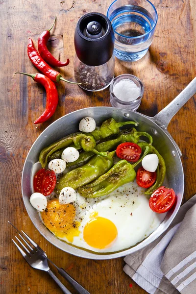 Breakfast in a frying pan. fried eggs with salad. fried green pe — Stock Photo, Image