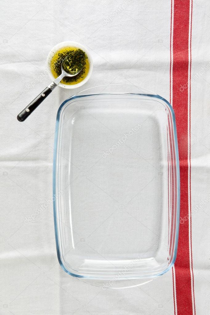 white kitchen towel on a dark background. glass pan and sauce wi
