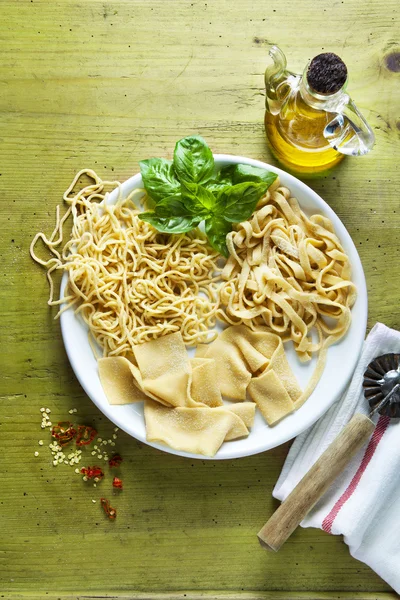 Various types of Homemade Fresh Pasta on the plate on a Green wo — Stock Photo, Image