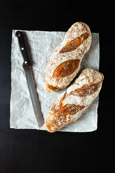 Zwart brood en een mes voor brood snijden — Stockfoto