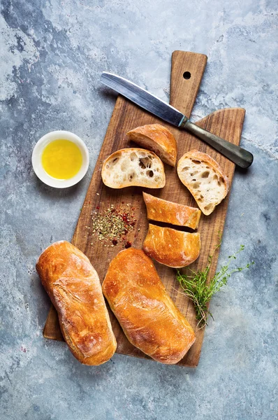 Sliced ciabatta bread on a cutting board on a gray stone backgro — Stock Photo, Image