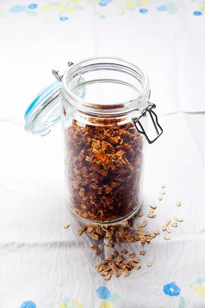 Granola em um jarro hermético em uma mesa com uma toalha de mesa — Fotografia de Stock