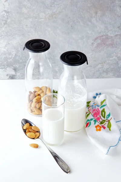 Fresh homemade almond milk in a transparent bottle and almonds. — Stock Photo, Image