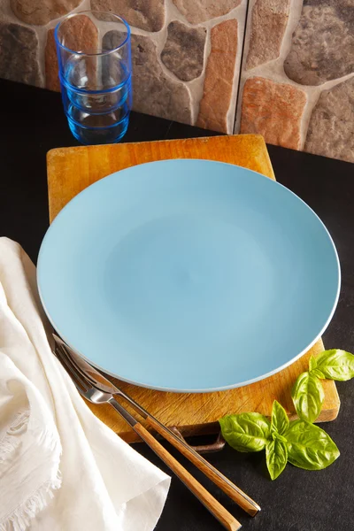 Ein Teller auf dem Tisch, Basilikumblätter und Gläser. Abendessen — Stockfoto