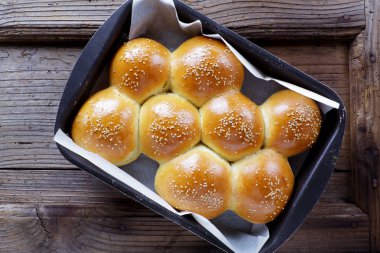 ahşap bir masa üzerinde bir fırın tepsisine Burger topuz