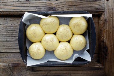 ahşap bir masa üzerinde bir fırın tepsisine ekmek buns