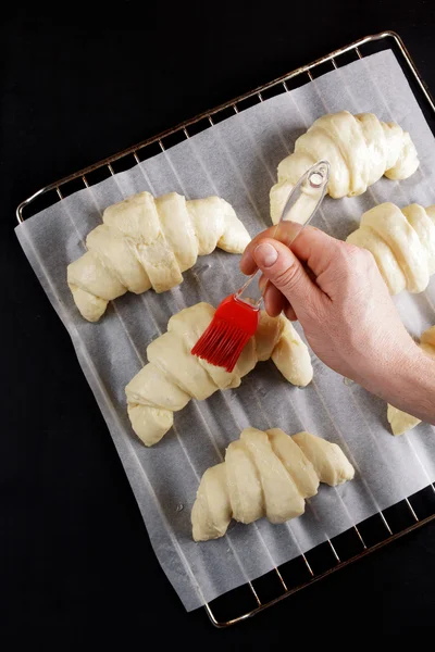 Pronto para assar croissants em uma assadeira para assar. escova — Fotografia de Stock