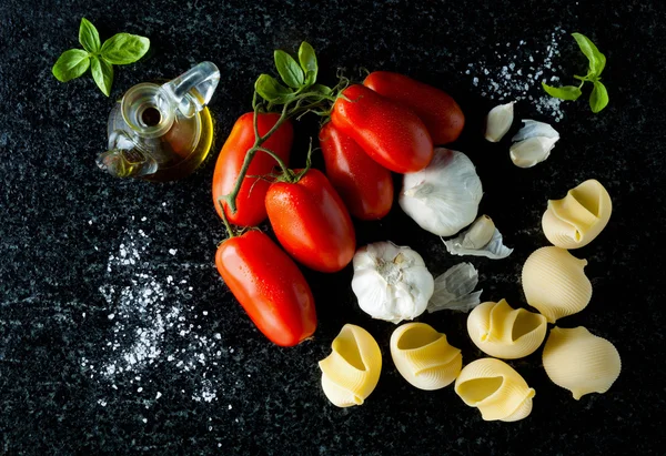 Ingredients on a black marble: ripe tomatoes, olive oil and garl — Stock Photo, Image