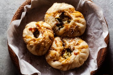 Baozi çörekleri, sebzeler ve mantarlar beton bir masanın üzerinde tahta bir sepetin içinde.
