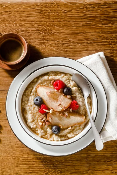 木のテーブルの上にカラメル梨とベリーのキノアのお粥 コーヒーと朝の朝食 — ストック写真