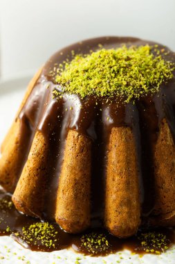 Fıstıklı beyaz bir tabakta haşlanmış haşhaşlı kek ve karamel. 