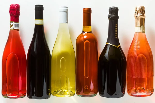 different bottles with alcohol on a white background: white, red, prosecco, pink, red, sherry. advertising