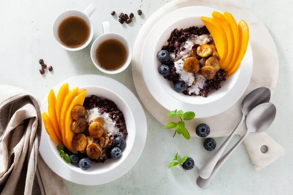 Siyah pirinç lapası, hindistan cevizi sütü ve mangolu Karayip tatlı kahvaltısı, kızarmış muz. Sağlıklı Jamaika mutfağı. Ve kahve.