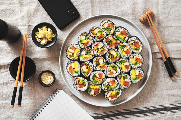 vegan sushi with tofu and avocado on a plate on a linen napkin. smartphone