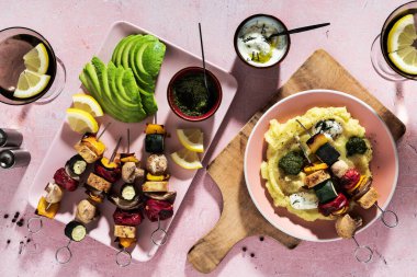 Tofu, mantar, avokado ve fesleğen soslu sebze kebabı. Tzatziki sosu ve pembe masada yaz kokteyli. Ve patates püresi.