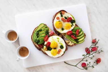 Avokado, domates ve fesleğen soslu kızarmış yumurtalı sandviç ve kahve.
